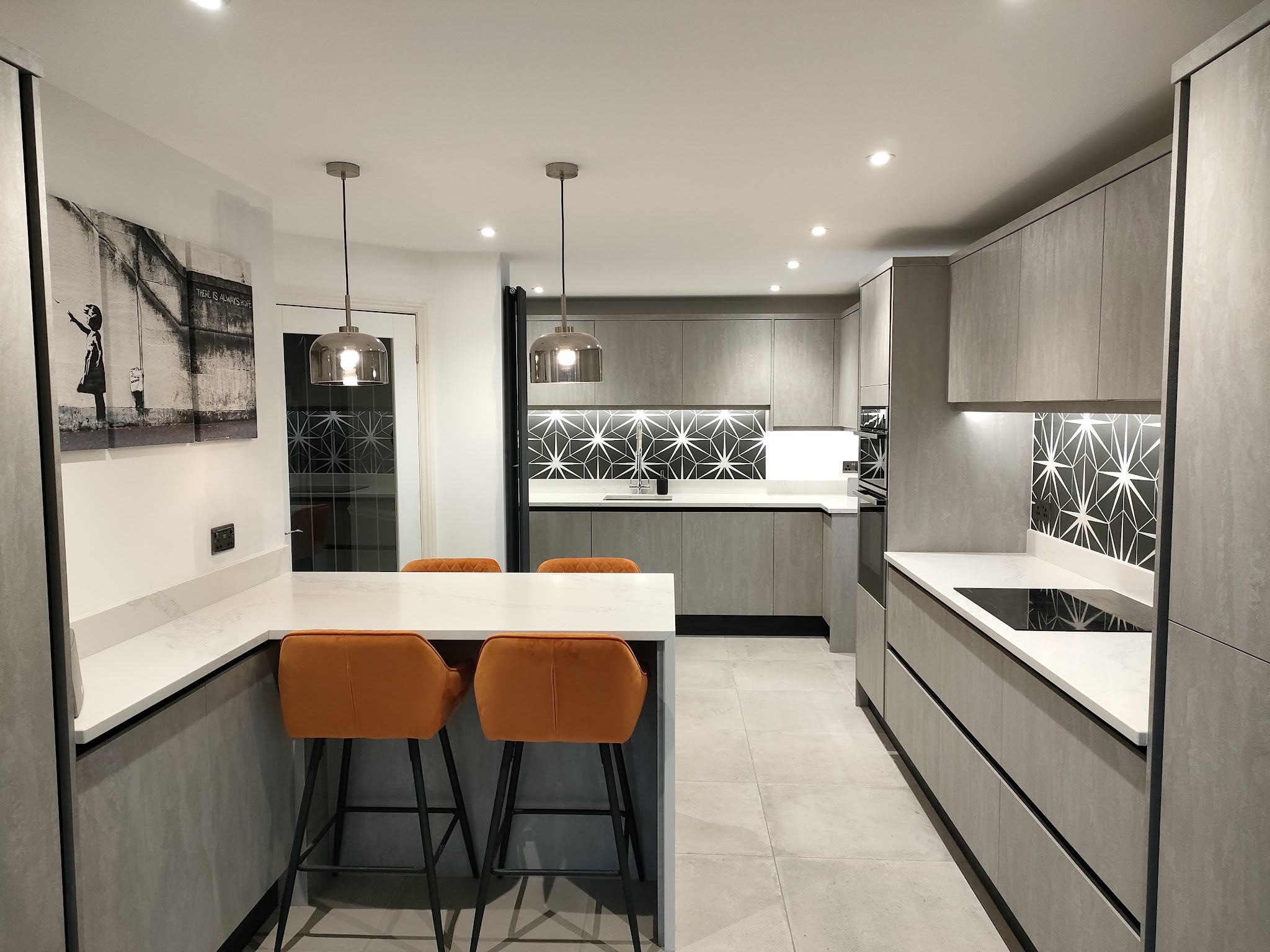 Grey kitchen with a white quartz breakfast bar and copper bar stools