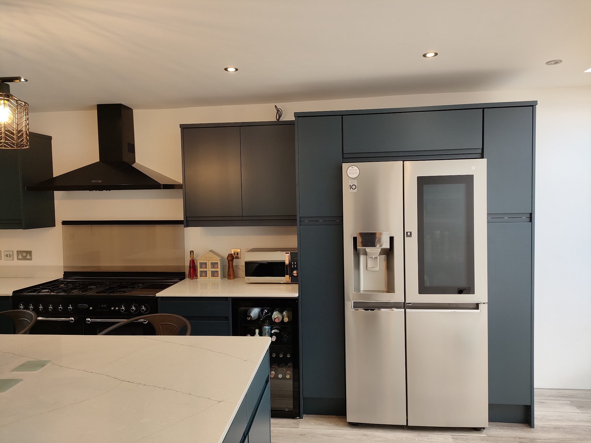 Dark kitchen with a tall larder run, range cooker and American fridge freezer